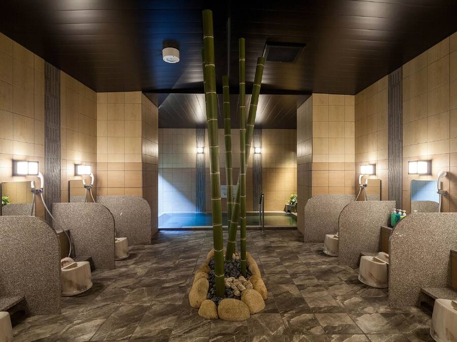 Een moderne badkamer met meerdere douchecabines, een centraal bamboepootje en inbouwverlichting.