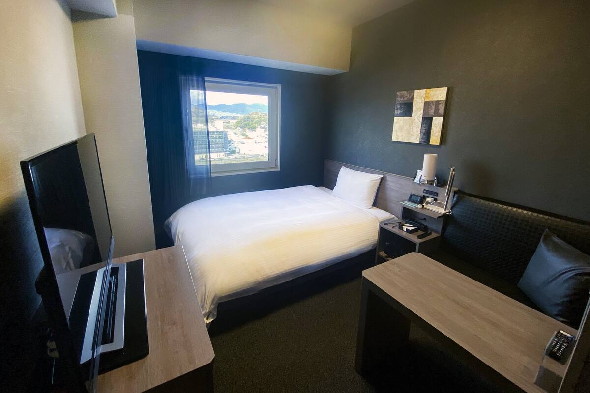 Ett hotellrum med en säng, ett nattduksbord, ett skrivbord och en tv.