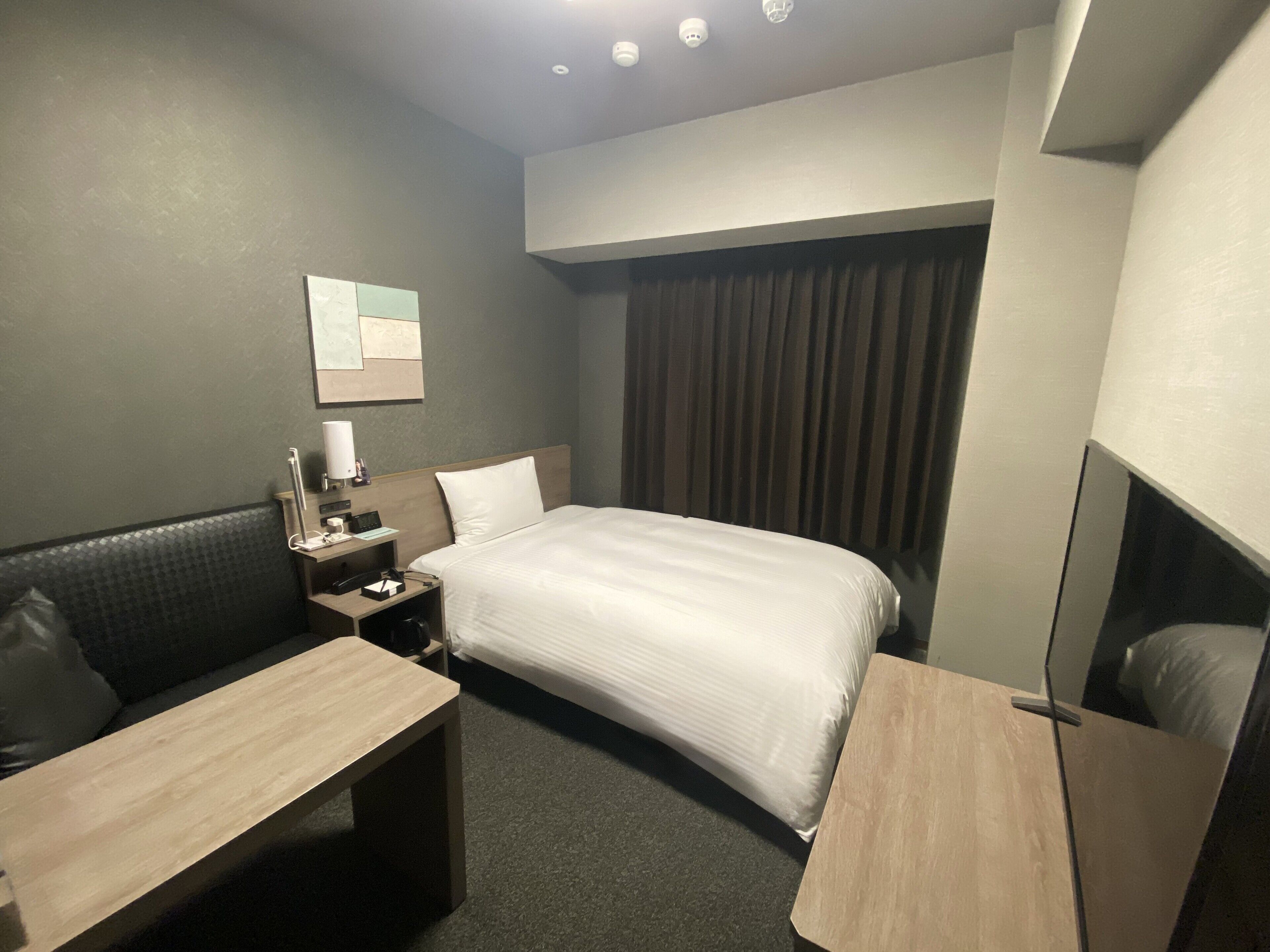 Une chambre d’hôtel comprenant un lit, un bureau, une chaise, une table de chevet et un miroir.
