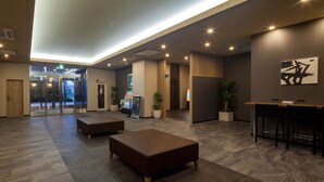 A spacious lobby with a modern design, featuring a reception desk, seating area, and a view of the entrance. - Hotel Route Inn Tsuyama Ekimae (Tsuyama)