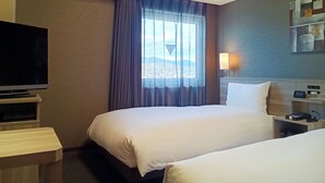 A hotel room with two beds, a TV, a bedside table, a lamp, and a window with curtains. - Hotel Route Inn Tsuyama Ekimae (Tsuyama)