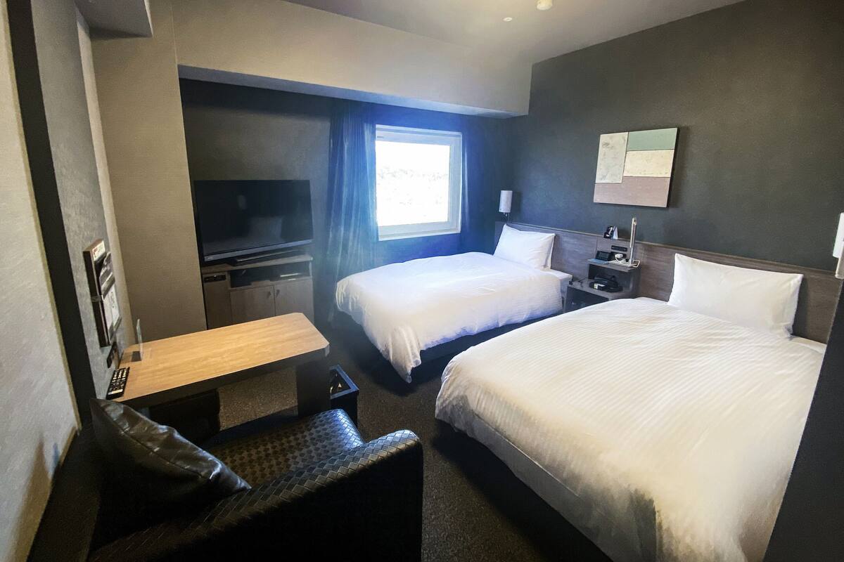 Ett hotellrum med två sängar, en TV, ett skrivbord och ett fönster.