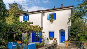 A two-story building with blue doors and windows, surrounded by greenery and stone walls. - Nice apartment in Kastav (Kastav)