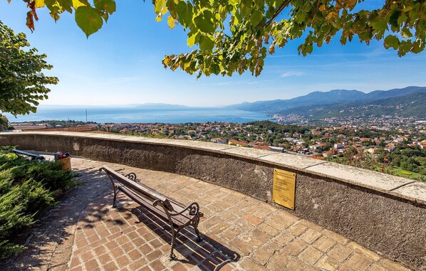 Un banco de piedra con vista a un pueblo costero, con una vista despejada del mar y montañas a lo lejos.