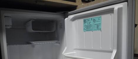 An open refrigerator with a control panel and a warning label.