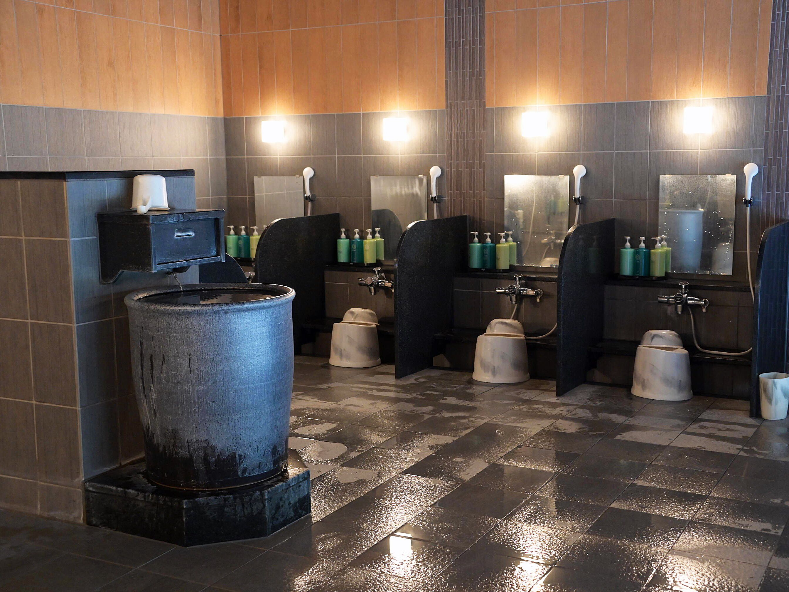 A public restroom with multiple sinks, hand dryers, and soap dispensers.