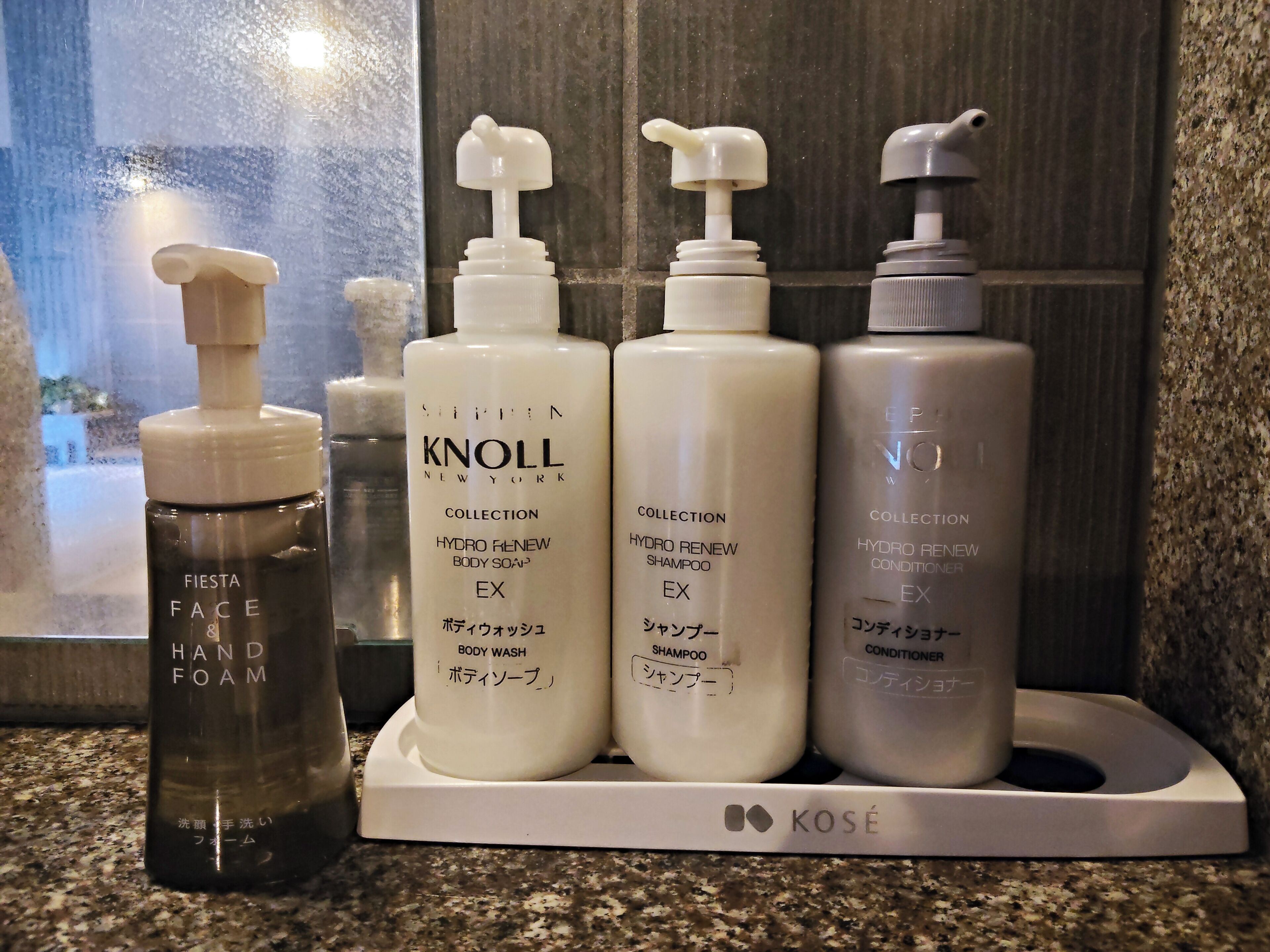 Un ensemble de produits de toilette disposés sur un comptoir, comprenant un savon pour les mains, un gel douche, un shampooing et un après-shampooing.