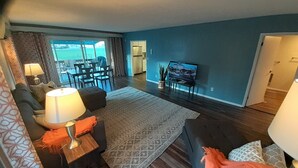 A living room with a sofa, a coffee table, a TV, and a dining area with chairs and a table. - Fishing Bungalow at Keller Ferry (Wilbur)