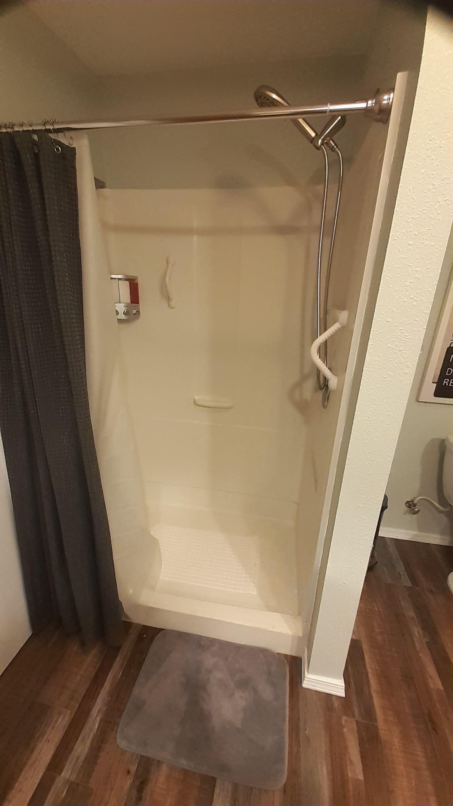Una ducha con puerta de cristal, un perchero y un panel de control.