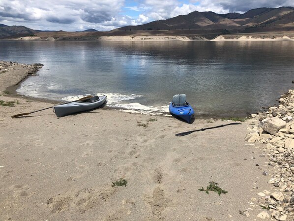 Un lago tranquilo con kayaks y una pala en la orilla.