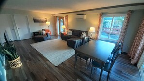 A spacious living room with a large dining table, a sofa set, and a patterned rug. - Fishing Bungalow at Keller Ferry (Wilbur)