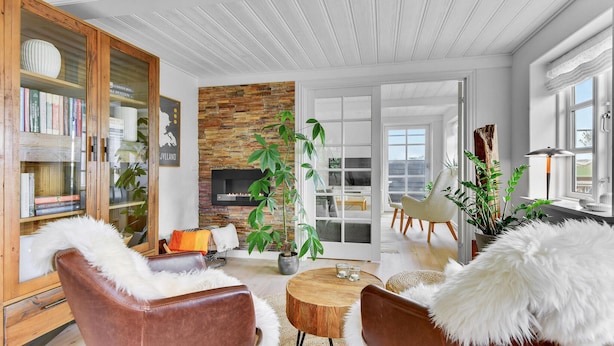 A modern living room with a fireplace, a bookshelf, and a dining area with a round wooden table.