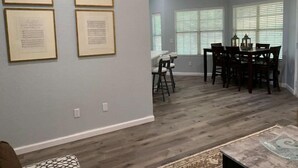 A dining area with a wooden table and chairs, framed documents on the wall, and a patterned rug on the floor. - Austin Home (Austin)