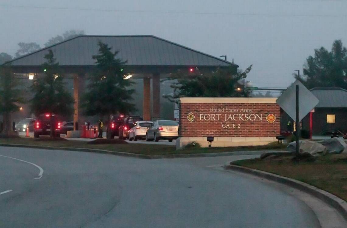 A sign for Fort Jackson Gate 2 with a parking lot and vehicles.