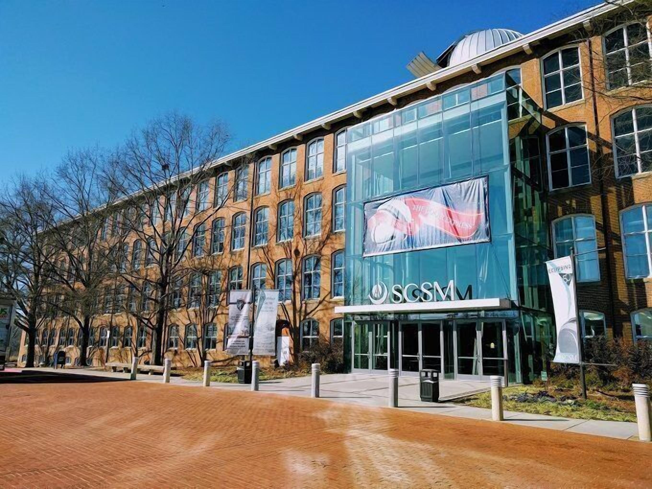 A modern building with a glass facade and a sign reading "SCSM".