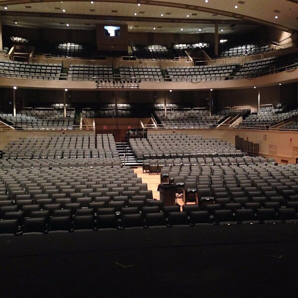 Un gran auditorio de varios niveles con asientos escalonados y una zona central para el escenario.