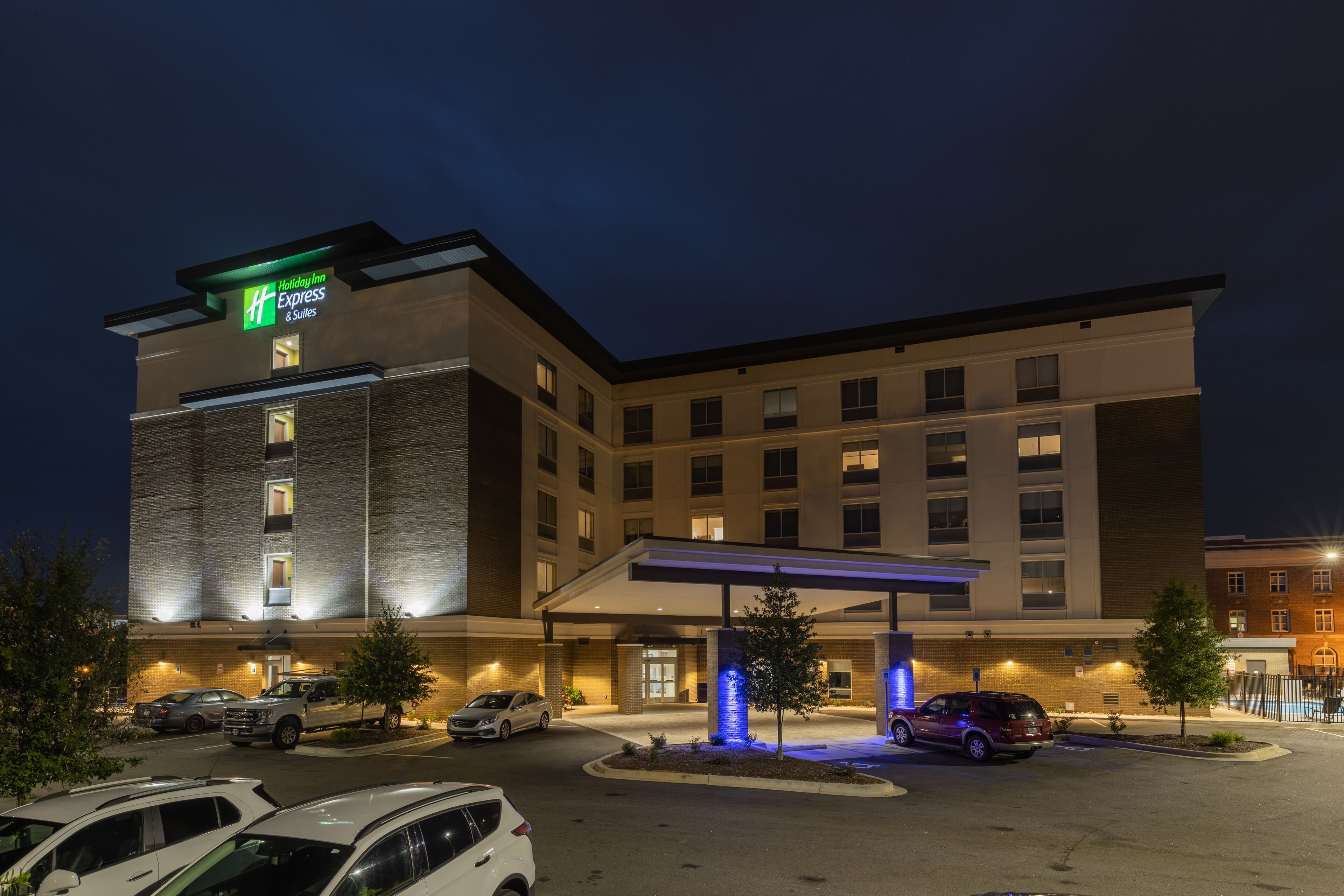 Un hôtel Holiday Inn Express doté d’une entrée abritée, de nombreux espaces de stationnement et d’une façade bien éclairée.
