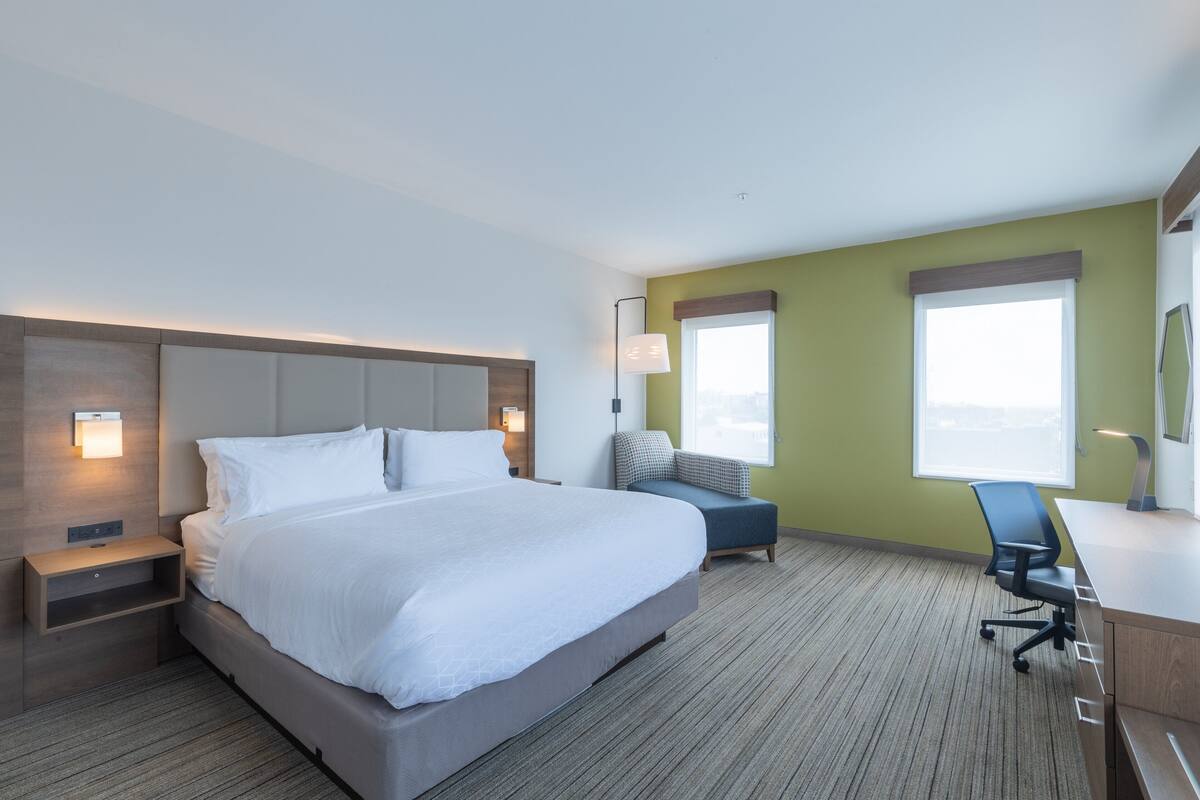 A hotel room with a large bed, bedside tables, a desk, and a chair.