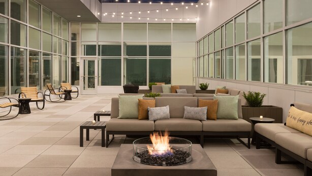 Un patio intérieur moderne doté d’un foyer, de sièges et de grandes fenêtres.