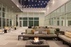 Un patio interior moderno con chimenea, asientos y ventanas amplias.