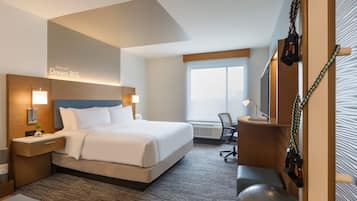 A hotel room with a large bed, a desk, a chair, a treadmill, and a window with a view.