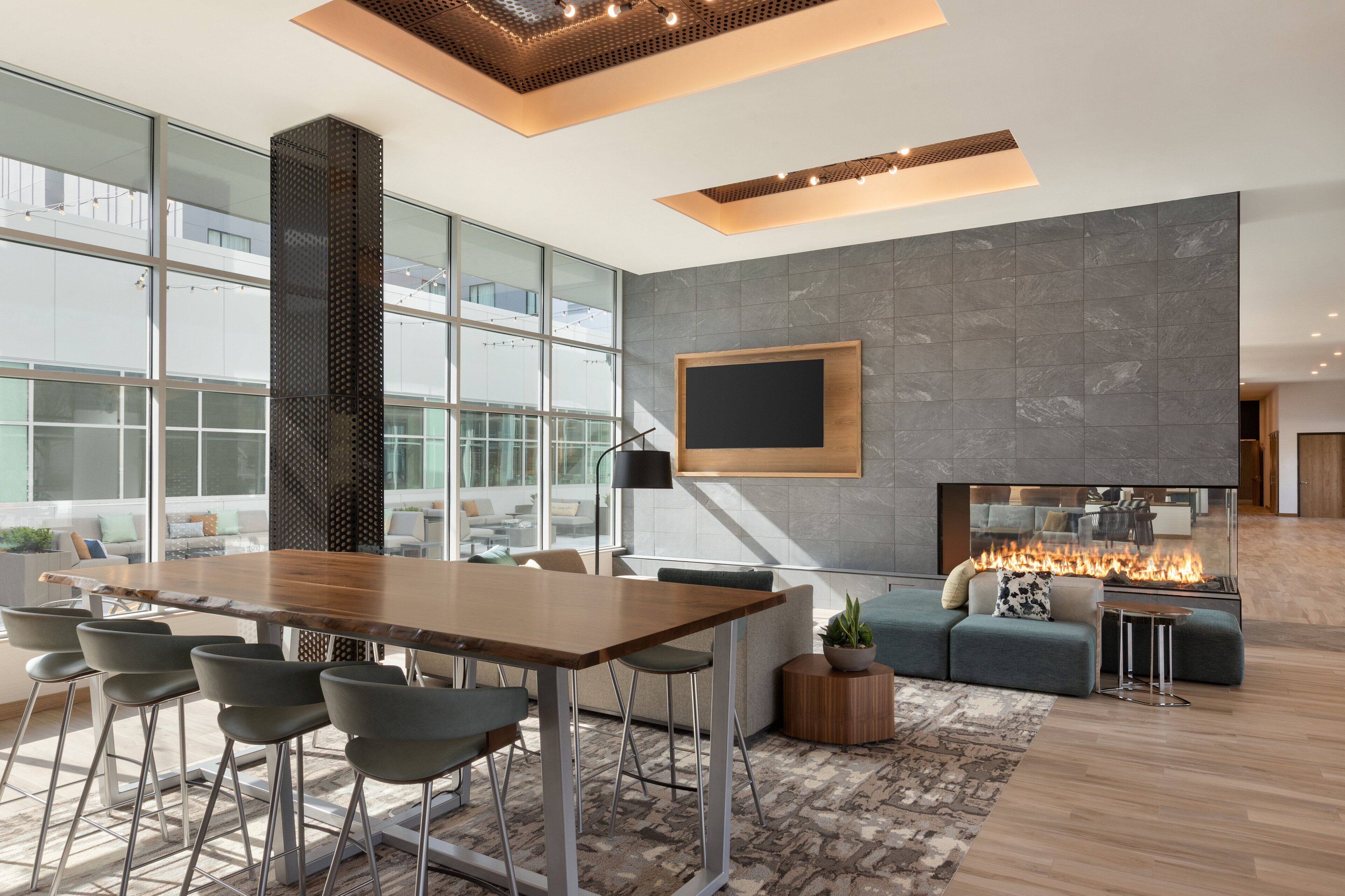 Een modern interieur met een grote eettafel, comfortabele zithoek, een open haard en grote ramen met uitzicht op de stad.