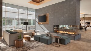 Un salon moderne doté d’une cheminée, de grandes fenêtres et d’un téléviseur à écran plat fixé au mur.
