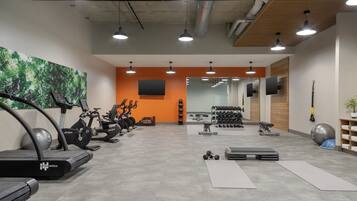 Une salle de sport équipée de tapis de course, d’haltères et de ballons d’exercice.
