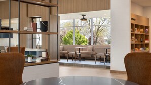 Un intérieur moderne comprenant un coin salon, une bibliothèque et une fenêtre donnant sur la verdure.