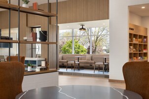 Un interior moderno con una zona de estar, una estantería y un ventanal con vistas a los árboles.