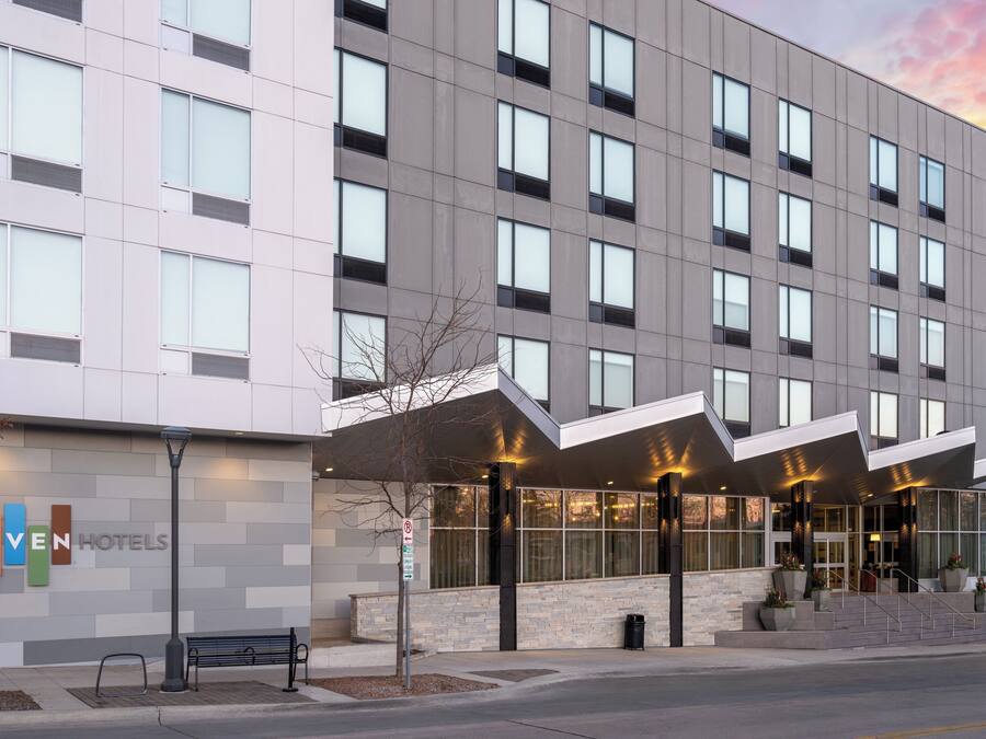 A modern hotel with a flat facade, large windows, and a covered entrance area.
