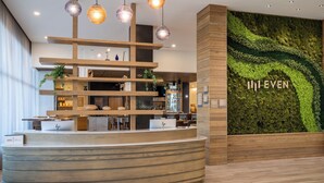 Un espace d’accueil doté d’un comptoir incurvé, d’étagères en bois et d’un mur recouvert de mousse verte sur lequel est inscrit le texte « I ♥ EVEN ».