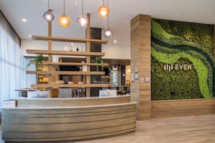 A reception area with a curved reception desk, wooden shelving, and a green moss wall with the text "I ♥ EVEN".