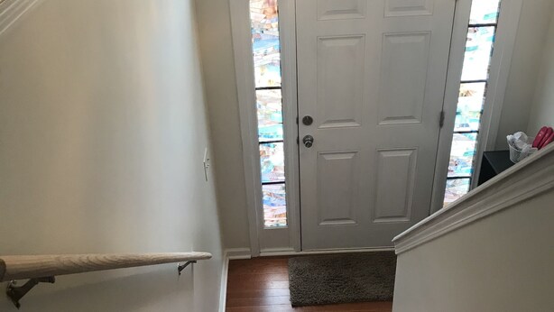 A wooden staircase leading to a white door with a stained glass window above.