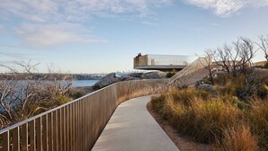 A pathway leading to a modern building with a view of the water and city skyline. - Designer Penthouse Overlooking Manly, the Ocean and Harbour (Manly)