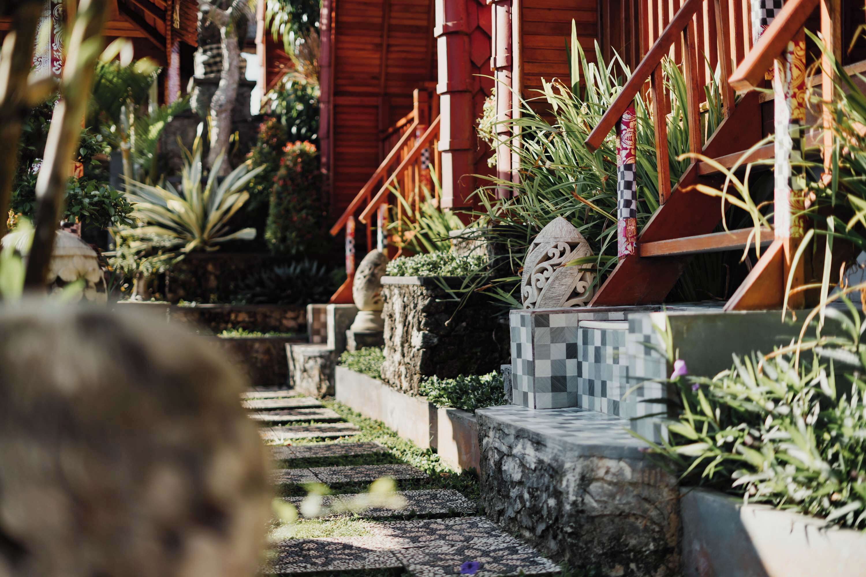 A pathway leading to a wooden building with a staircase and potted plants.