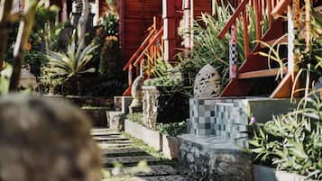 Un sendero que lleva a una construcción de madera con una escalera y plantas en macetas.