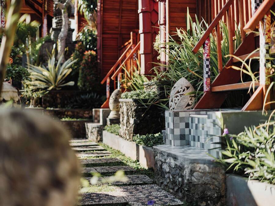 Un sendero que lleva a una construcción de madera con una escalera y plantas en macetas.