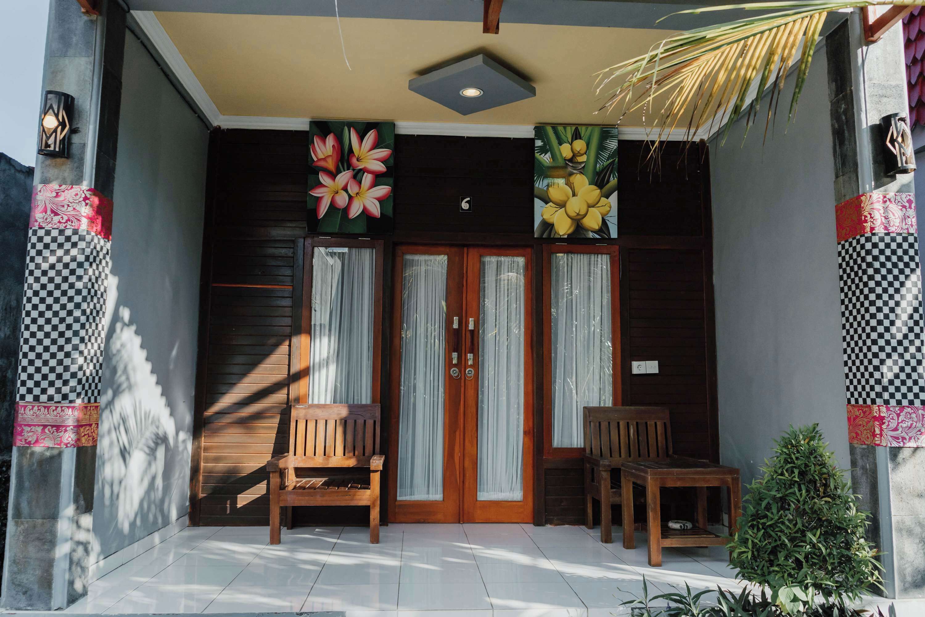 A building entrance with two wooden doors, a small bench, and a potted plant.