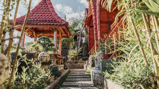 A pathway leading to a traditional red-roofed pavilion surrounded by lush greenery and stone steps. - Sentulan Garden Villa (Penida Island)