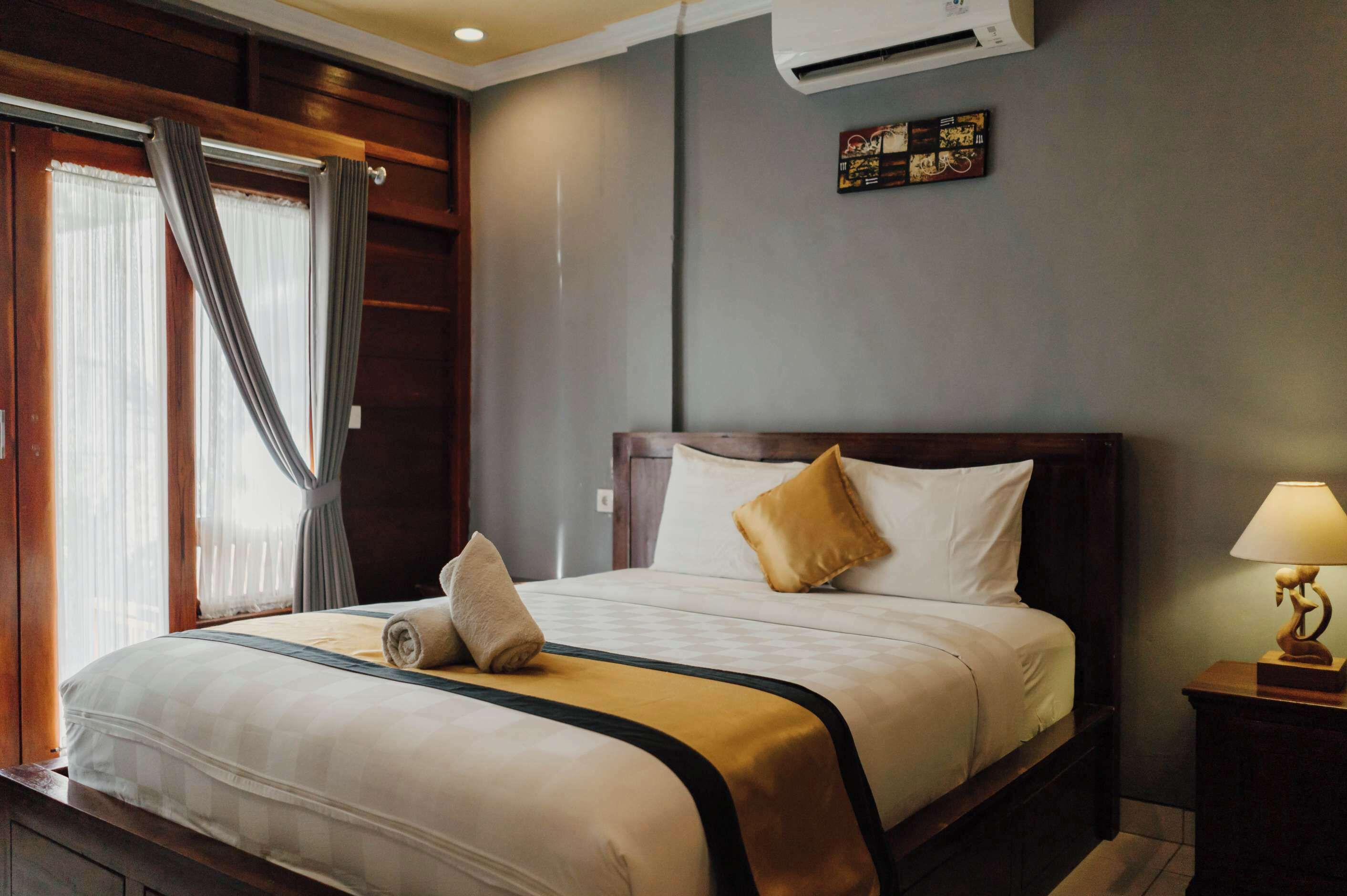 Une chambre d’hôtel avec un lit, des rideaux, un climatiseur, une table de chevet et une horloge murale.