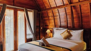 A wooden-paneled room with a bed, curtains, and a nightstand with a lamp. - Sentulan Garden Villa (Penida Island)