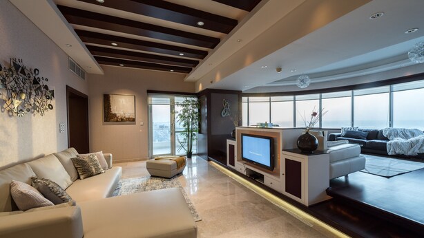 A modern living room with a large TV, comfortable seating, and a view of the city.