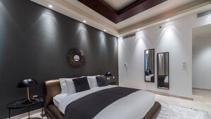 A modern bedroom with a large bed, a round mirror, and a nightstand.