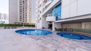 A modern building with a rooftop pool area, including two swimming pools and outdoor seating.