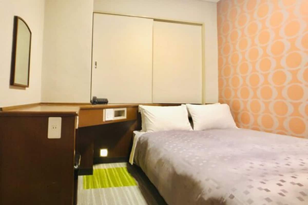 Ein Hotelzimmer mit Bett, Schreibtisch, Kleiderschrank und Spiegel.
