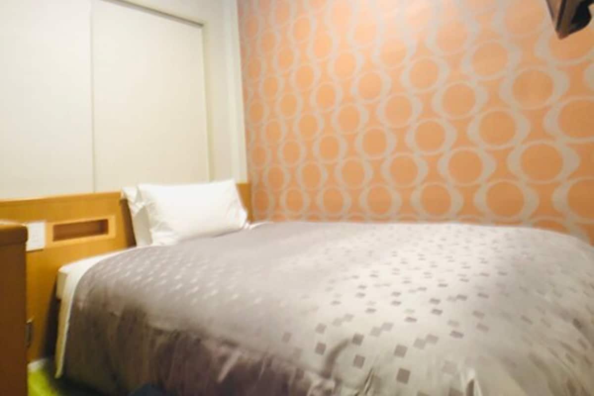 Ein Hotelzimmer mit einem Bett, einem Holz-Kopfteil und einer Wand mit Muster.