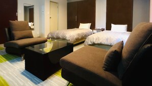 Une chambre d’hôtel avec deux lits, un canapé, une table basse et une armoire.