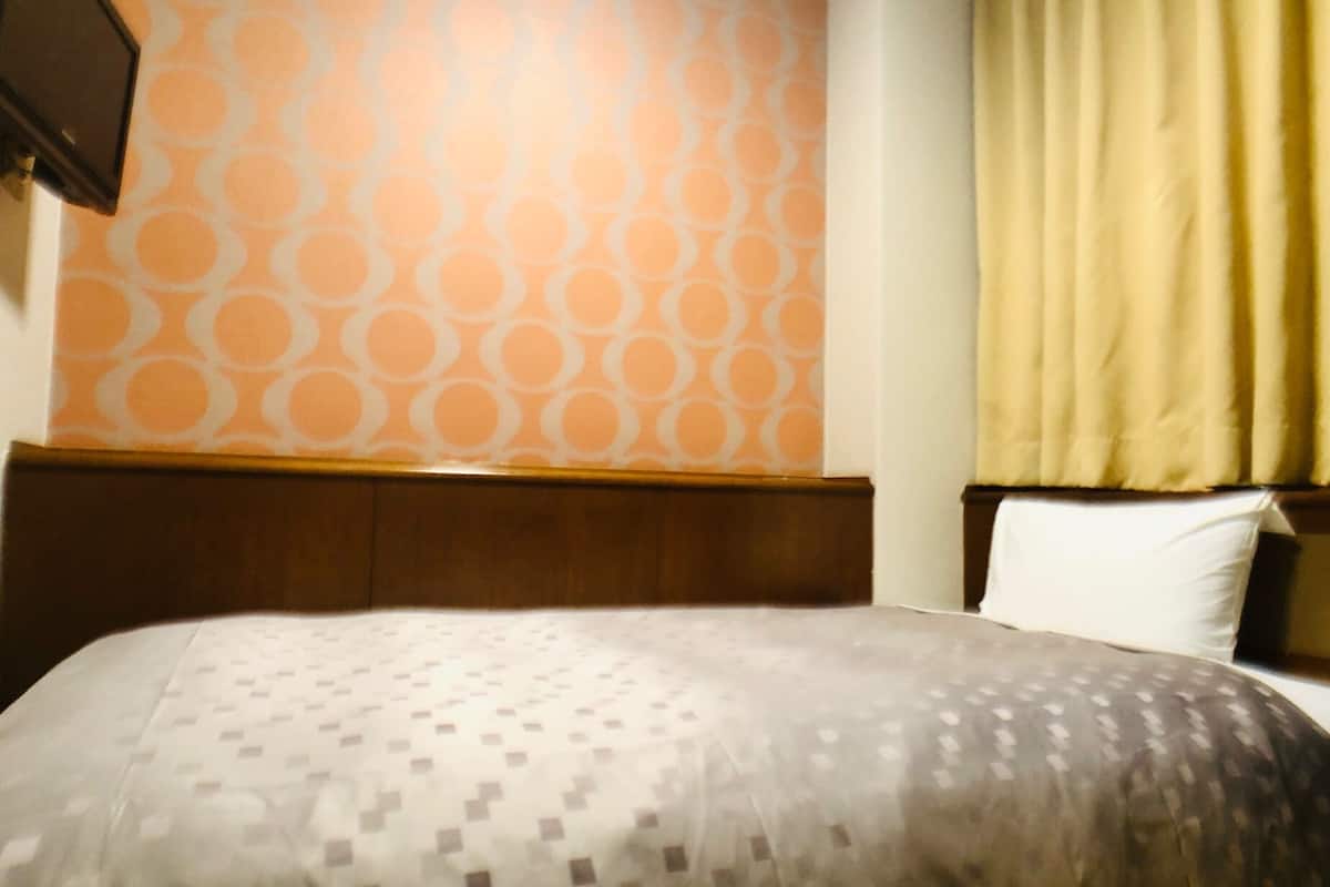 Ein Hotelzimmer mit Wand- und Bettdekor, einem hölzernen Kopfteil und einem weißen Kissen.