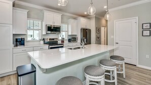 A modern kitchen with white cabinetry, a large island, bar stools, and pendant lighting. - Stunning Corner Townhome |Gulf Views |Beach Parking Pass |Dog Friendly |Free Golf |Beach Club |Pools (Pensacola)